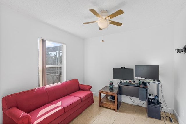 living area featuring a textured ceiling, light tile patterned floors, baseboards, and ceiling fan