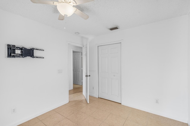 spare room with light tile patterned flooring, visible vents, a textured ceiling, and ceiling fan