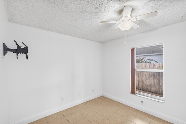 spare room featuring baseboards, a textured ceiling, ceiling fan, and light tile patterned flooring