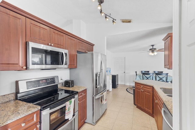 kitchen featuring light stone counters, light tile patterned floors, visible vents, lofted ceiling, and stainless steel appliances