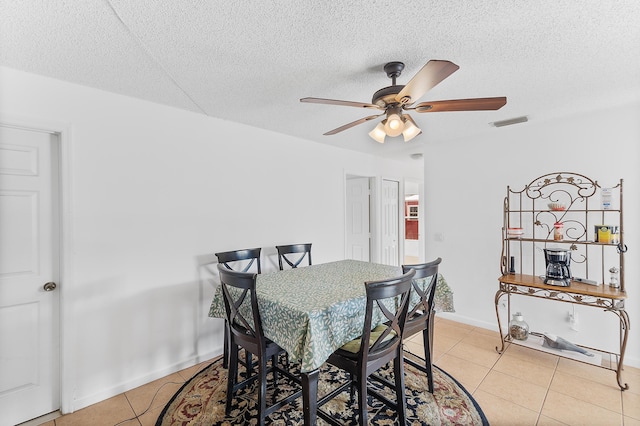 dining room featuring visible vents, a ceiling fan, a textured ceiling, light tile patterned floors, and baseboards