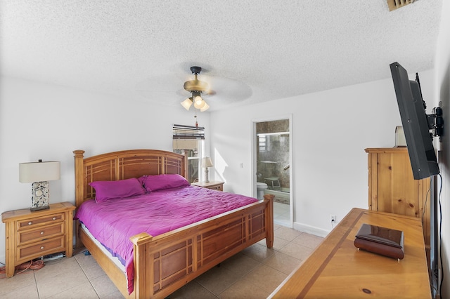 bedroom with baseboards, ensuite bath, light tile patterned flooring, ceiling fan, and a textured ceiling