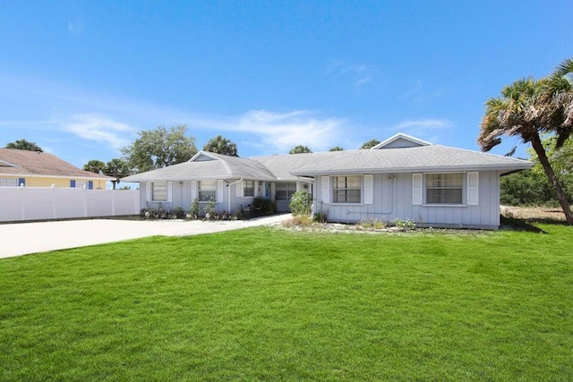 ranch-style home with a front lawn, concrete driveway, fence, and board and batten siding