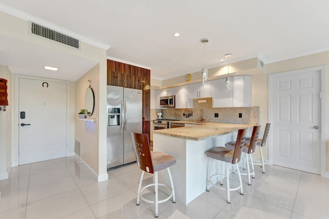 kitchen with visible vents, appliances with stainless steel finishes, a peninsula, and ornamental molding