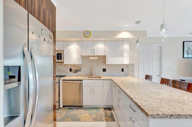 kitchen featuring crown molding, appliances with stainless steel finishes, a peninsula, white cabinetry, and a sink