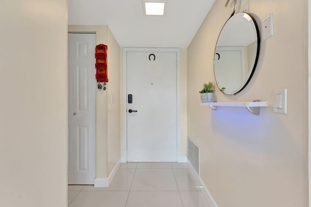 doorway featuring light tile patterned floors, visible vents, and baseboards