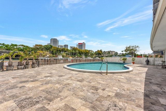 community pool with a patio, a city view, and fence