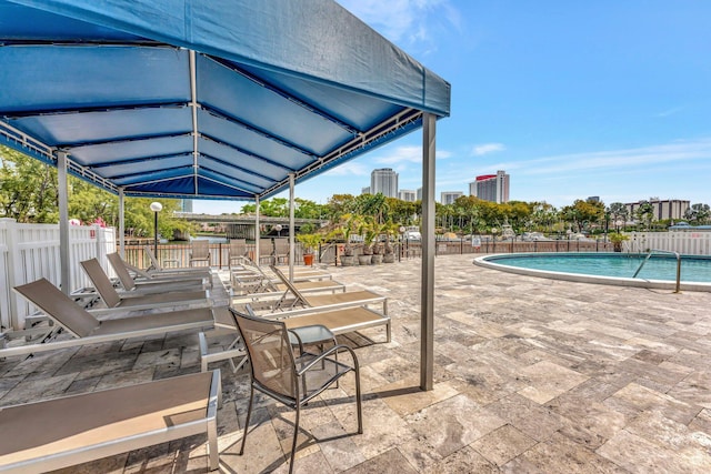 pool featuring a patio area, a city view, and fence