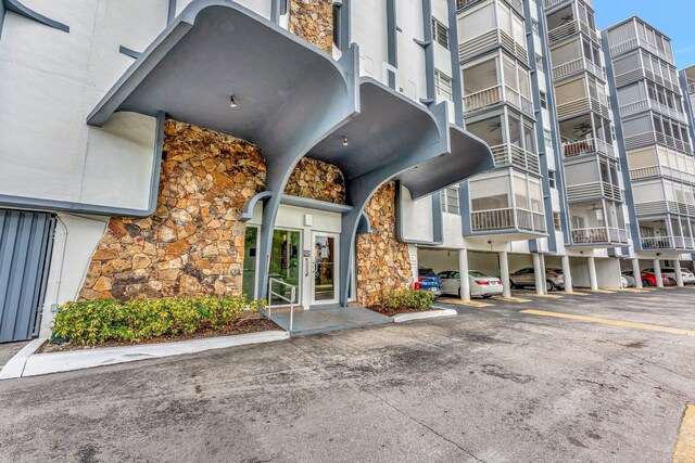 entrance to property with stucco siding, stone siding, and a parking lot