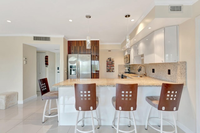 kitchen featuring visible vents, ornamental molding, a peninsula, stainless steel appliances, and a sink