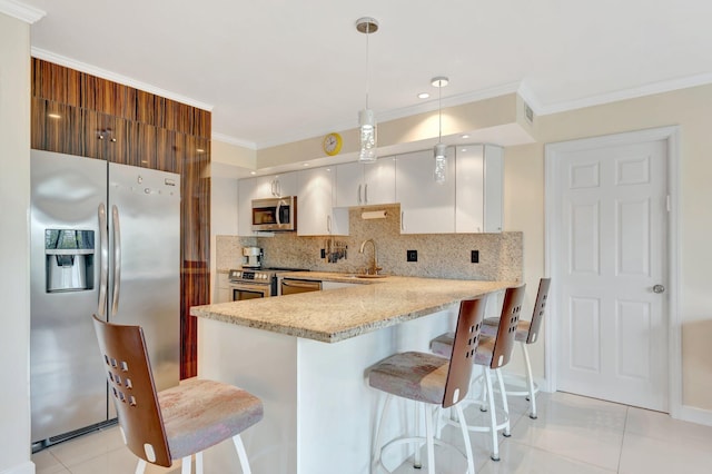 kitchen with a breakfast bar, ornamental molding, a sink, appliances with stainless steel finishes, and backsplash