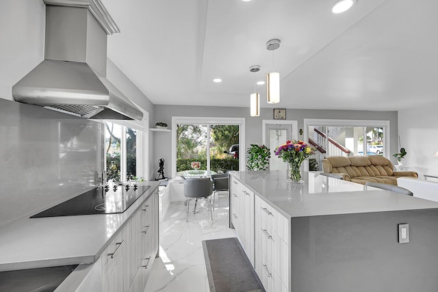 kitchen featuring light countertops, wall chimney range hood, black electric stovetop, and marble finish floor