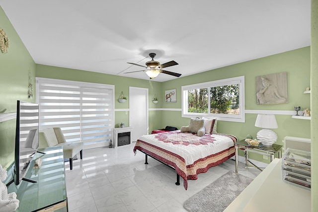 bedroom with marble finish floor, a fireplace, and a ceiling fan