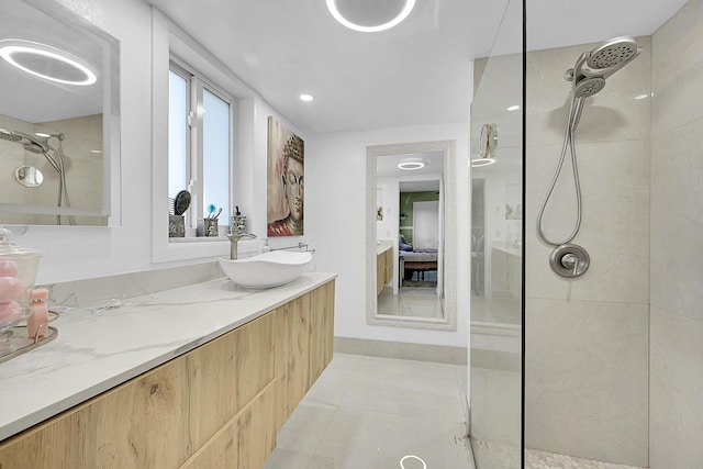 ensuite bathroom with vanity, tile patterned floors, tiled shower, and connected bathroom