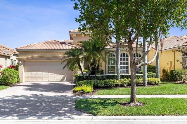 view of front of property featuring decorative driveway, a garage, stucco siding, and a tile roof