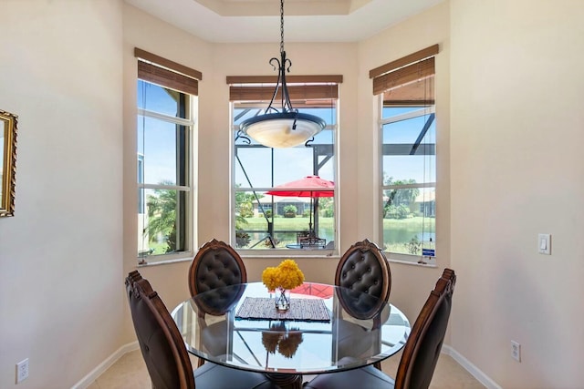 dining area featuring a tray ceiling and baseboards