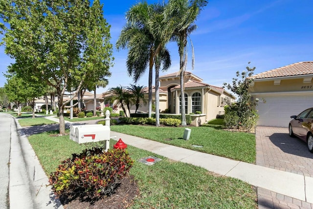 mediterranean / spanish house featuring stucco siding, a tile roof, decorative driveway, and a front lawn