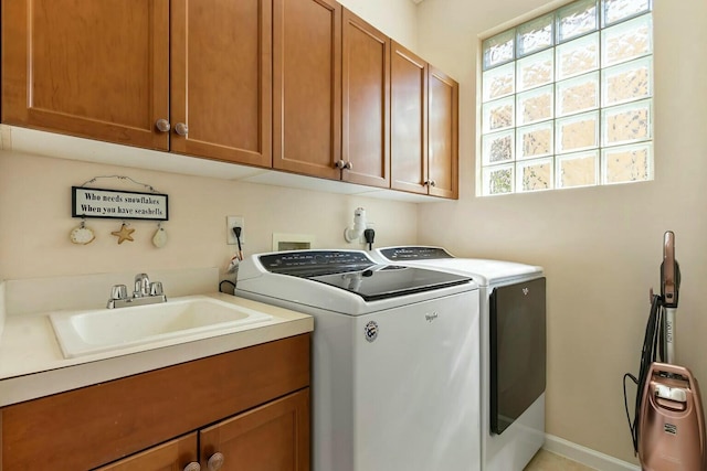 clothes washing area featuring a sink, a healthy amount of sunlight, cabinet space, and washer and clothes dryer