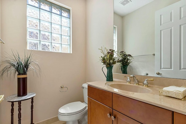 half bathroom with visible vents, plenty of natural light, toilet, and vanity