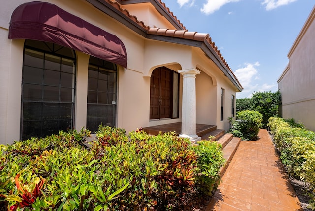 view of exterior entry featuring stucco siding and a tile roof