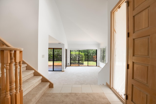 entryway with light carpet, stairway, high vaulted ceiling, and light tile patterned floors