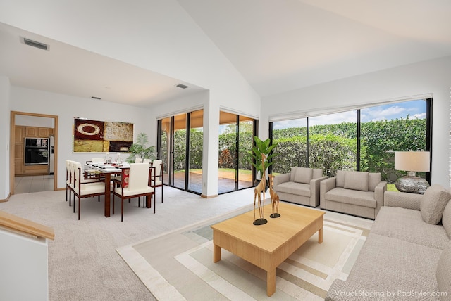 living room with visible vents, light carpet, and high vaulted ceiling