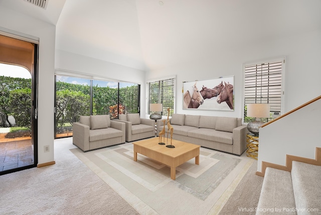 carpeted living room featuring visible vents, a towering ceiling, and stairs