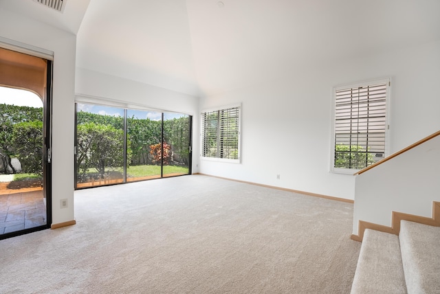 unfurnished living room with visible vents, baseboards, carpet, and high vaulted ceiling