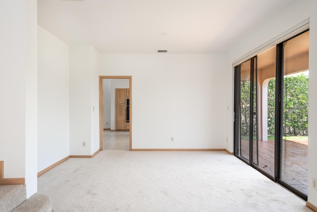 unfurnished room with visible vents, light carpet, and baseboards