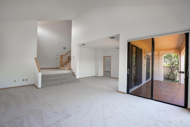 unfurnished living room with stairway, carpet flooring, visible vents, and high vaulted ceiling