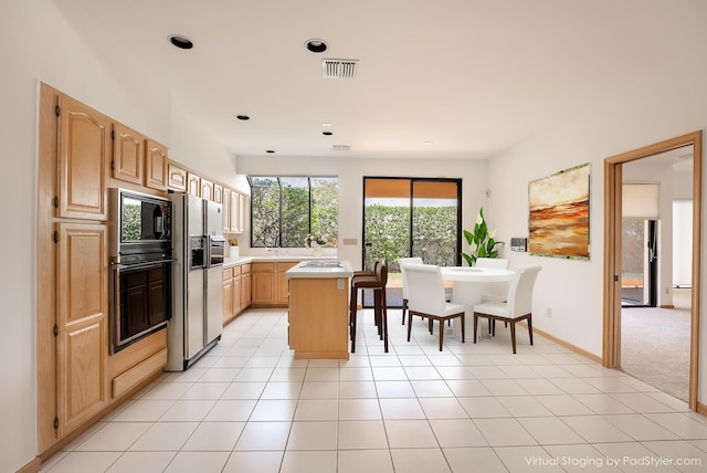 kitchen with visible vents, black microwave, light brown cabinetry, light countertops, and light tile patterned flooring