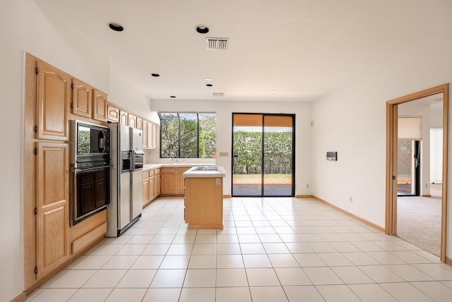 kitchen featuring light tile patterned floors, visible vents, a kitchen island, light brown cabinetry, and light countertops