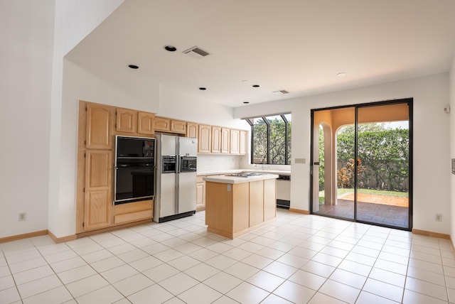 kitchen with visible vents, light brown cabinets, a kitchen island, stainless steel fridge with ice dispenser, and light countertops