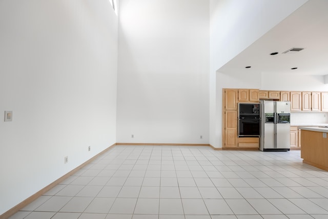 kitchen with baseboards, light brown cabinetry, light countertops, black microwave, and fridge with ice dispenser