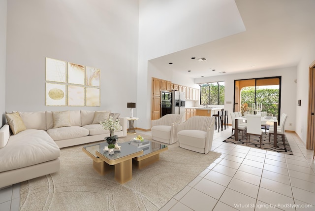 living room featuring visible vents, baseboards, a high ceiling, and light tile patterned flooring