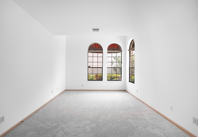 carpeted spare room featuring baseboards and visible vents