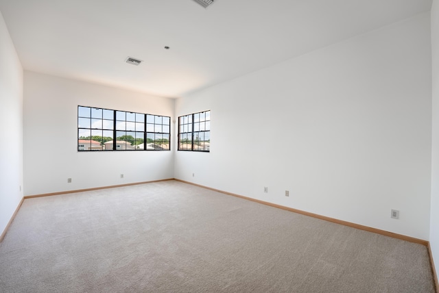 spare room featuring visible vents, light carpet, and baseboards