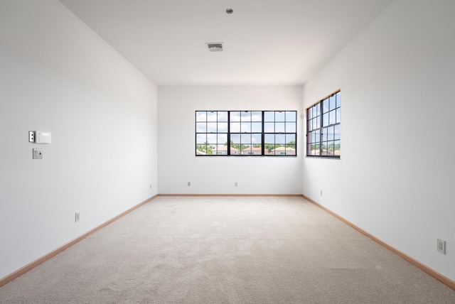 spare room with light carpet, visible vents, and baseboards