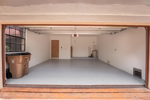 garage with visible vents, a garage door opener, and water heater