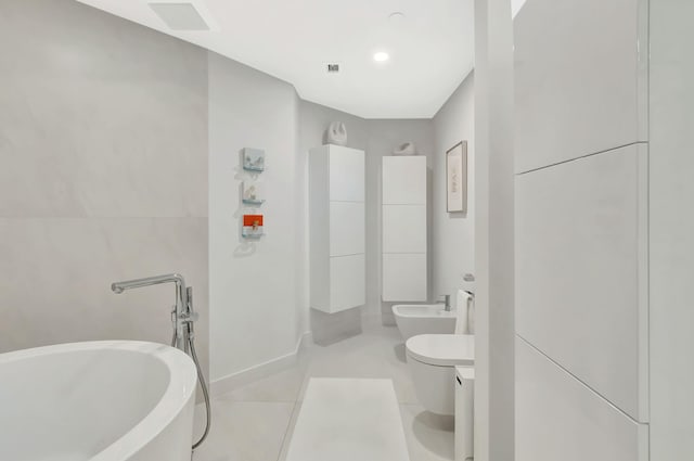 bathroom featuring visible vents, toilet, a bidet, tile patterned flooring, and a soaking tub