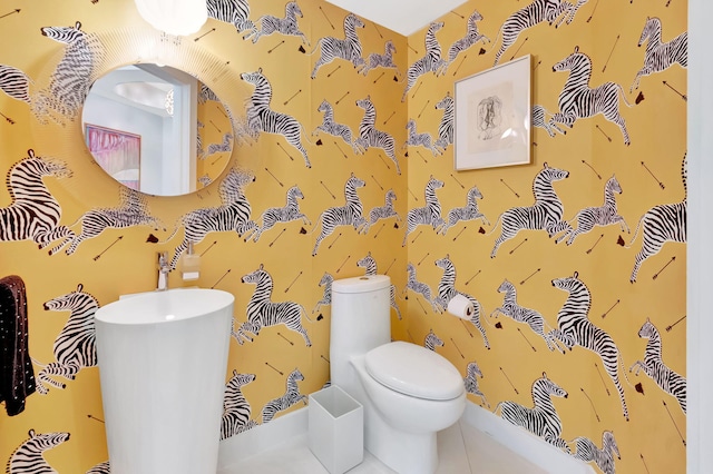 half bath featuring wallpapered walls, toilet, and tile patterned flooring