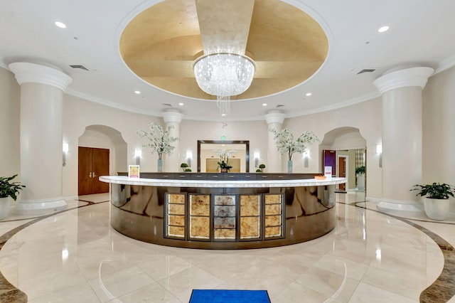 welcome area featuring visible vents, a chandelier, and decorative columns