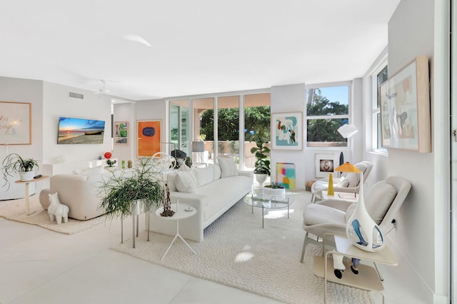 living room featuring ceiling fan, a healthy amount of sunlight, visible vents, and expansive windows