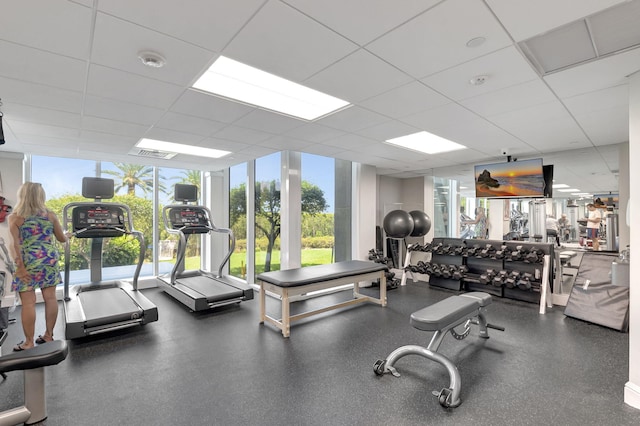 workout area featuring visible vents, a wall of windows, and a paneled ceiling