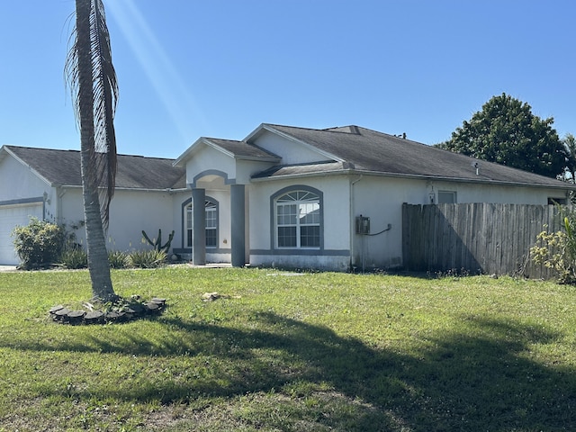 view of front of house with stucco siding, an attached garage, a front yard, and fence