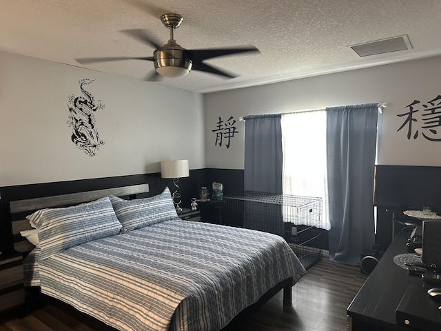 bedroom featuring visible vents, dark wood-type flooring, a textured ceiling, attic access, and ceiling fan