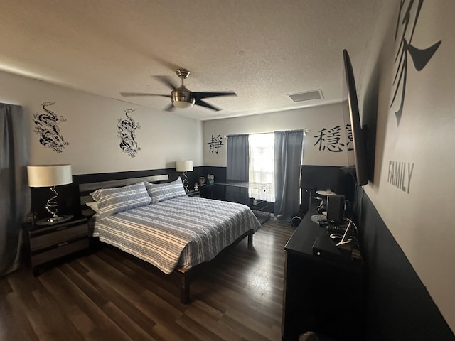 bedroom featuring dark wood finished floors, a ceiling fan, visible vents, and a textured ceiling