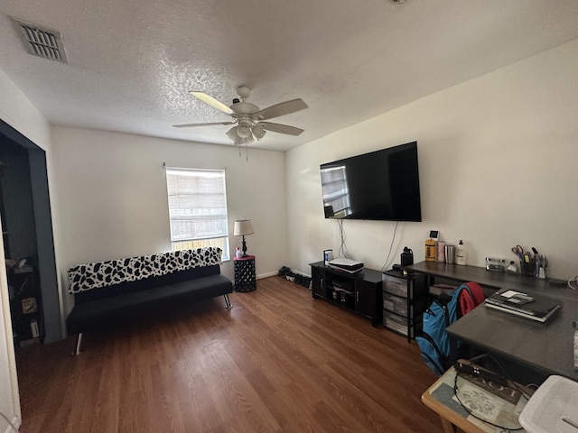 living room featuring wood finished floors, baseboards, visible vents, ceiling fan, and a textured ceiling