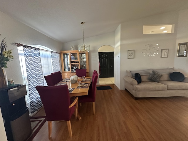 dining room with a notable chandelier, lofted ceiling, and wood finished floors