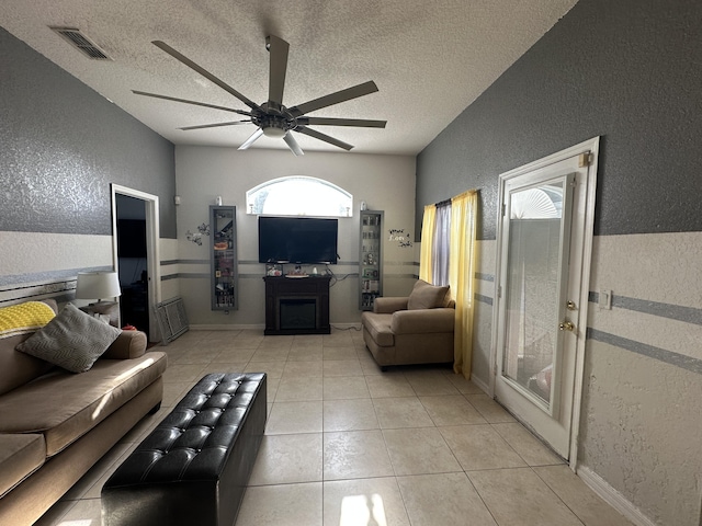 living room featuring visible vents, a textured ceiling, a ceiling fan, and a textured wall